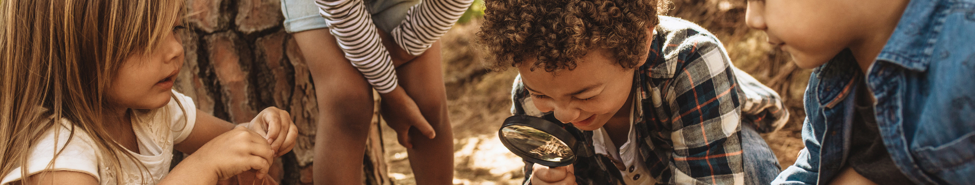 Kids exploring in forest with a magnifying glass